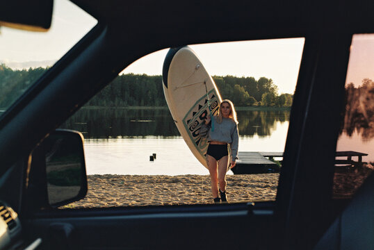 Woman Carrying SUP at Sunset Lakeside Beach
