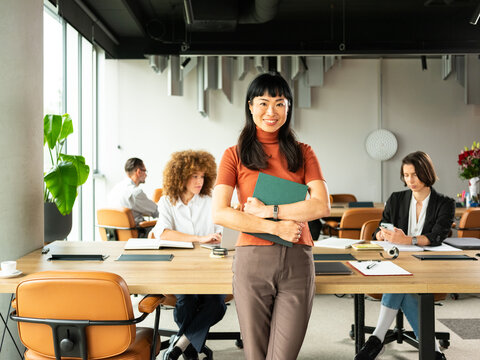 Confident Business Woman Standing With Folders In Office