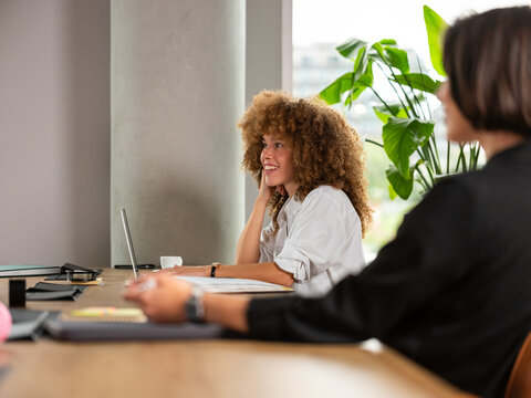  Woman With Curly Hair Smiles At Office Desk