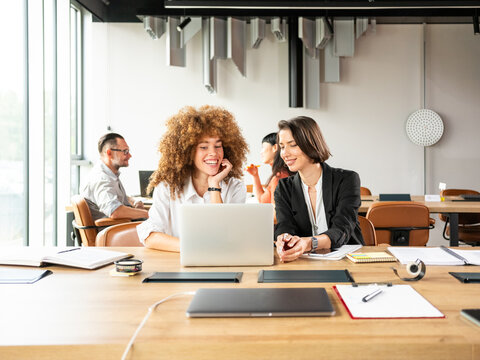 Collaborative Office Moment: Two Women Share Laughs 