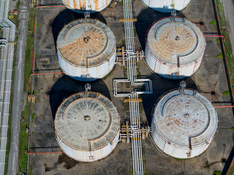 Aerial view of weathered, circular storage tanks connected by a network of pipes basking under the sun, Kalochori, Thessaloniki, Greece.