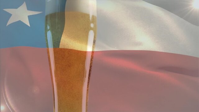 Tall pilsner glass developing foam while Chilean flag waving and sun glinting, promoting Chile beer