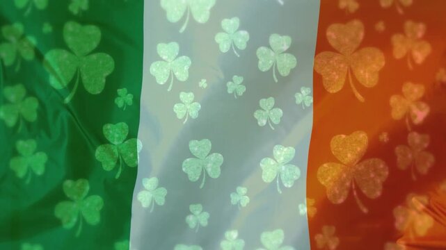Irish tricolor flag with shamrocks rippling from breeze, highlights shifting, marking St Patrick's