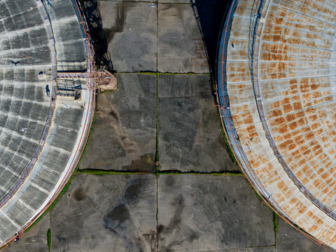 Aerial view of weathered, circular structures with contrasting textures and tones, set against a concrete landscape, Kalochori, Thessaloniki, Greece.