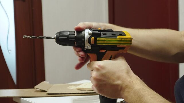 Hands of Caucasian man turning ratchet ring of screwdriver and adjusting maximum torque close up. Changing tightening force to maximum value for drilling.