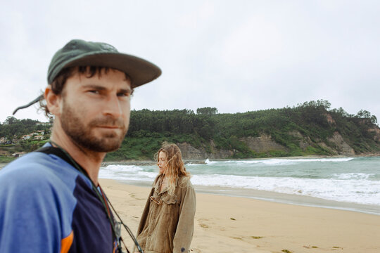 Couple standing on a windy beach with cliffs in the background