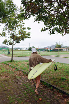Woman walking with surfboard on a cloudy day