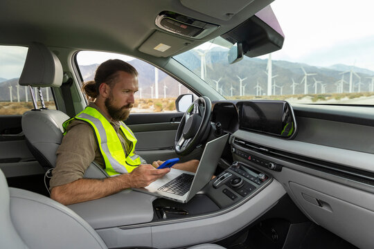 Wind Turbine Technician working remote laptop in car 
