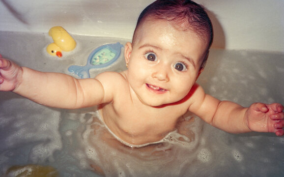 Overhead portrait of baby in bath reaching toward camera