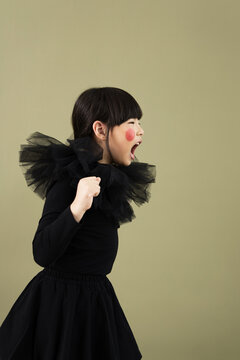 Child expressing joy with vibrant costume in studio setting