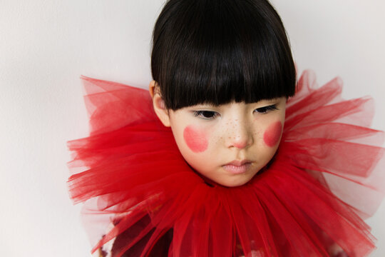 Young girl wearing a red tulle collar with rosy cheeks 