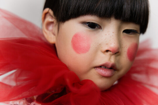 Young girl wearing a red tulle collar with rosy cheeks 