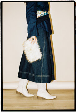 Woman in denim outfit holding fur bag