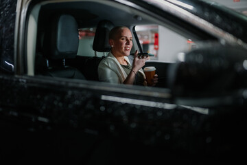 Woman driving car, holding coffee and talking on phone, symbolizing busy urban lifestyle and multitasking at night