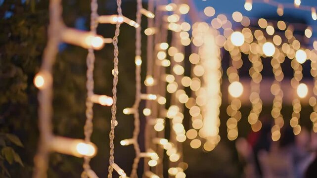 Golden bokeh lights twinkling on festive outdoor string display at dusk