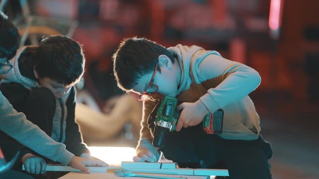 Young boy student learning carpentry using drill