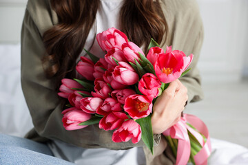 Woman with bouquet of pink tulips at home, closeup