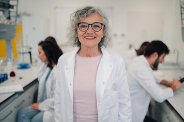 Fototapeta premium Smiling senior scientist woman in laboratory background