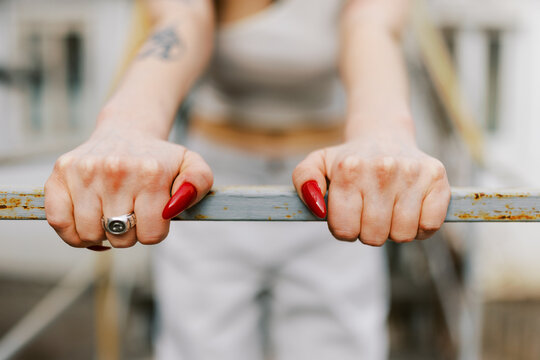 Woman With Red Nails Grips a Bar in an Outdoor Workout Session
