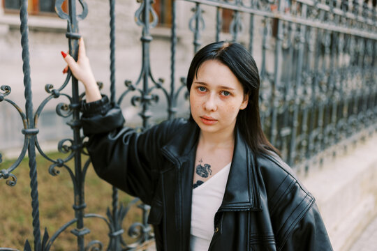 Young Woman Posing by Ornate Iron Fence in Urban Setting