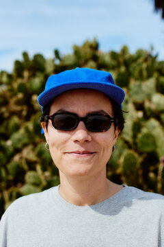 Portrait of a woman wearing sunglasses and a blue cap
