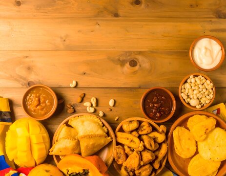 Platos tradicionales africanos con mango, empanadas, salsa de man&iacute; y aperitivos en mesa de madera