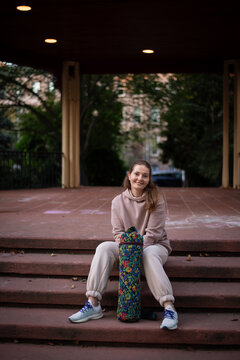 Woman sitting on steps with floral yoga mat carrier
