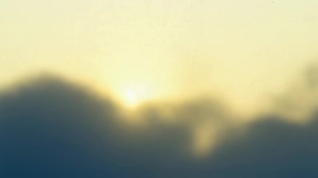 Rising sun backlighting low cloud bank at horizon, revealing soft halo and rim light