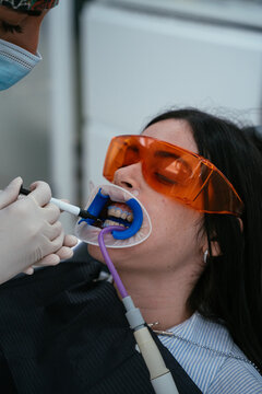 Dentist applying teeth whitening gel on patient