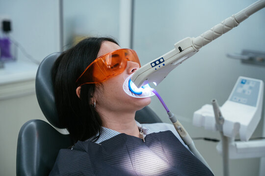 Woman receiving dental teeth whitening treatment with uv light