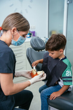 Dentist teaching child about proper dental hygiene using model