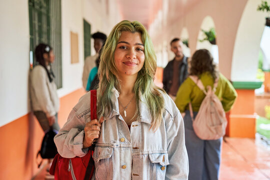 Smiling student with green hair in school hallway