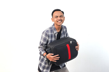Fototapeta premium Asian man wearing a shirt with a playful expression is holding a suitcase on an isolated white background.