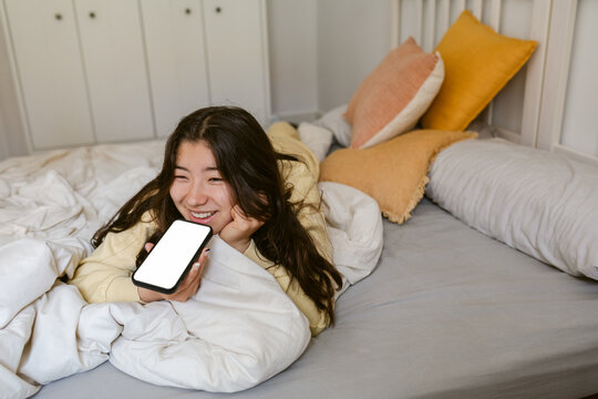 Smiling Girl hoding phone bed