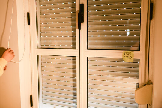 Hand Reaching for Cord by Closed Window With Blinds in a Cozy Room