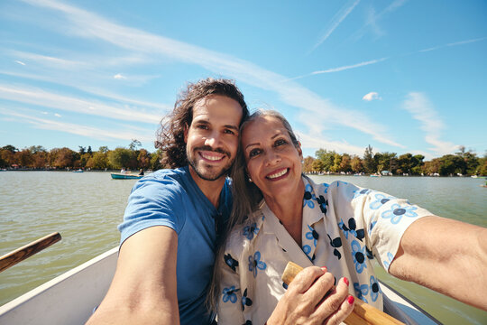 Mother and son taking selfie while rowing on lake