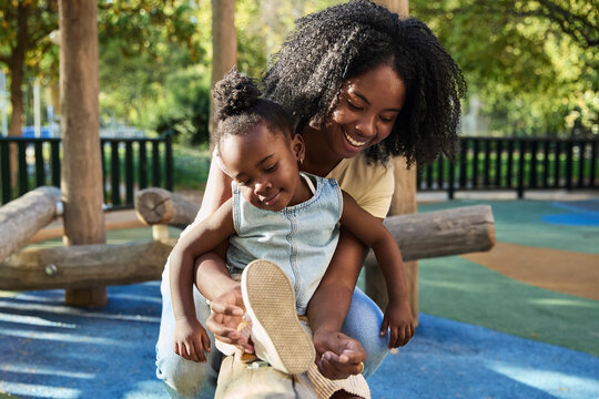 Woman fixing child&rsquo;s shoelaces at playground