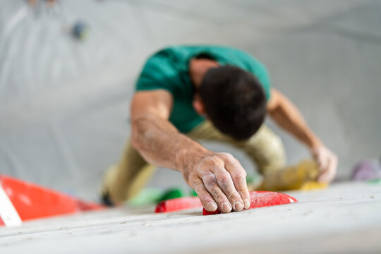 Man gripping a boulder hold, climbing on an indoor wall