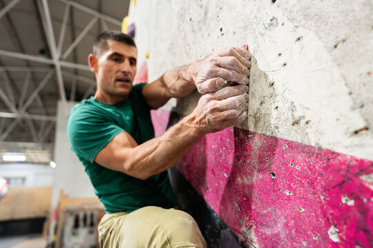 Male athlete bouldering indoors, gaining strength and fitness