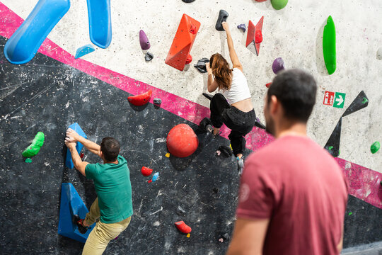 People bouldering on a climbing wall in a gym