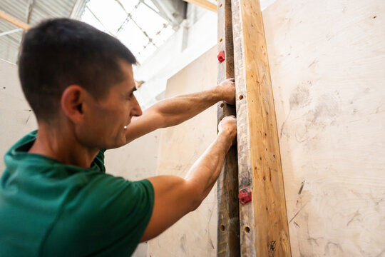 Man training on wooden fingerboard for climbing strength