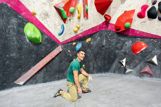 Man kneeling resting inside bouldering climbing gym