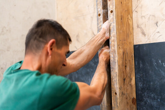 Man training strength on a climbing fingerboard