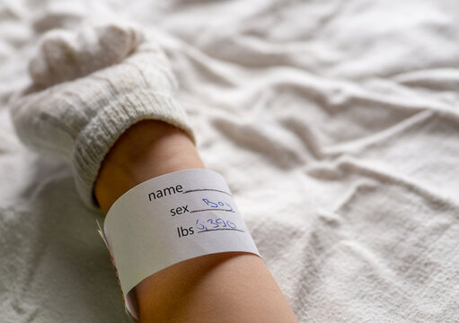 Newborn hand with maternity hospital tag.