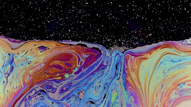 Soap bubble breaking apart in slow motion near collapse. Its fragile surface fragments, stretches and thins, revealing the final stage before bursting completely.