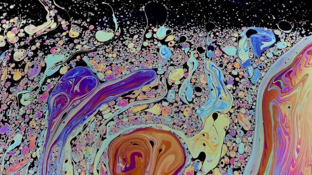 Soap bubble breaking apart in slow motion near collapse. Its fragile surface fragments, stretches and thins, revealing the final stage before bursting completely.