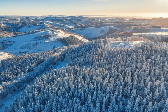 Aerial view of snow-blanketed forests and rolling hills create a serene winter wonderland, Winterberg, North Rhine-Westphalia, Germany.