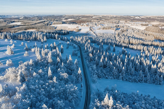 Aerial view of a road winding through snow-covered forests, the landscape painted with winter's icy brush, Winterberg, North Rhine-Westphalia, Germany.
