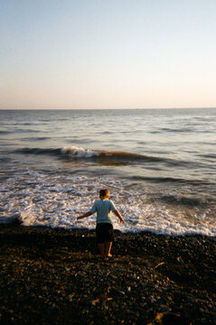 Boy standing in front of seaside during sunset