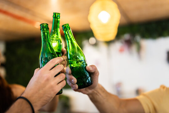 Friends toasting green bottles celebrating together on party